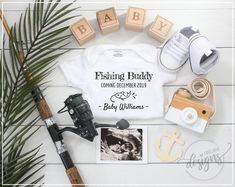 a baby's first birthday shirt, fishing rod, and other items laid out on a table