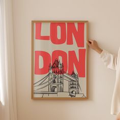 a woman standing in front of a poster with the words london on it and a tower bridge