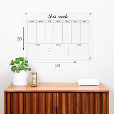 a wooden cabinet with a whiteboard on it and a potted plant next to it