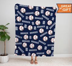 a woman standing in front of a blanket with baseballs on it