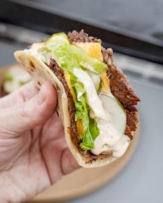 a hand holding a taco filled with lettuce and cheese