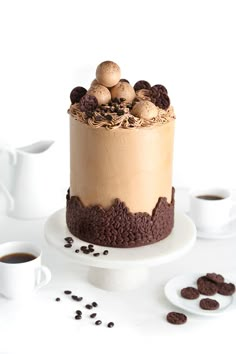 there is a cake on the table with coffee beans around it and two mugs next to it