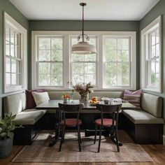 a dining room table with two chairs and a bench in front of the bay window