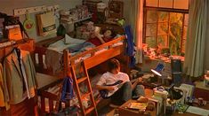 a young man sitting on the floor in front of a bunk bed reading a book