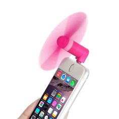 a hand holding an iphone with a pink fan attached to it