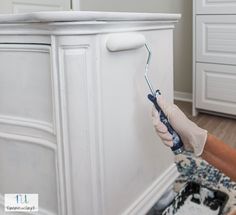 a person in white gloves painting a cabinet with blue and white paint on the wall