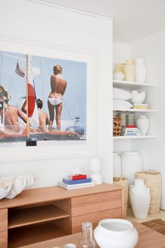 a living room filled with furniture and white vases on top of wooden shelves next to each other