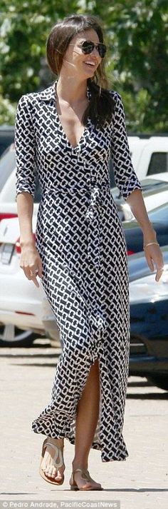 a woman walking across a parking lot in a dress