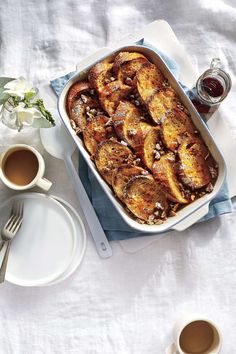 there is a casserole on the table with two cups of coffee