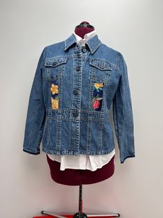 Denim jacket with embroidered floral insets and raw sleeve hems Measurements: Chest - 44" Shoulder to hem - 23.5" Spring Patchwork Denim Jacket With Long Sleeves, Spring Patchwork Long Sleeve Denim Jacket, Casual Floral Patchwork Outerwear For Spring, Denim Blue Long Sleeve Outerwear With Floral Embroidery, Long Sleeve Denim Blue Outerwear With Floral Embroidery, Denim Blue Floral Embroidery Long Sleeve Outerwear, Spring Denim Jacket With Floral Embroidery, Long Sleeve Denim Jacket With Floral Embroidery For Fall, Spring Cotton Outerwear With Floral Applique