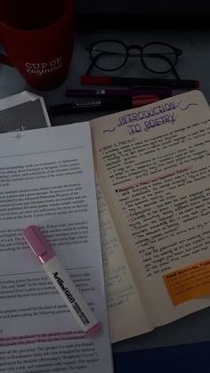 an open book sitting on top of a table next to a cup and pen with eyeglasses