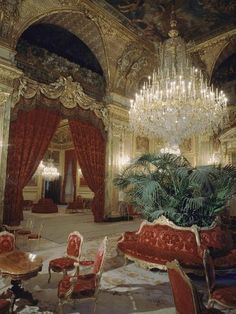 an ornate room with chandelier and red chairs