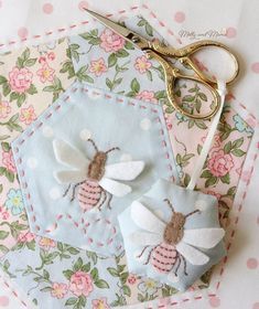 a pair of scissors sitting on top of a piece of fabric next to some flowers