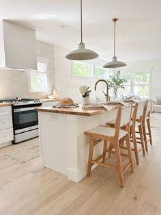 a kitchen with white walls and wooden floors has an island in front of the stove