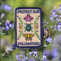 a patch with the words protect our polluniators on it in front of some purple flowers