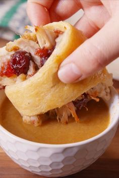 a person is dipping something into a bowl of soup with their fingers on the food