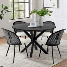 a black table with four chairs and a potted plant on it in front of a white brick wall