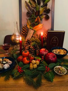 a table topped with fruit and vegetables next to a candlelight display on top of a wooden table