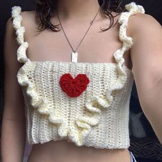 a woman wearing a crochet top with a red heart on it