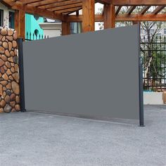 a large screen in front of a pile of firewood on the ground next to a building