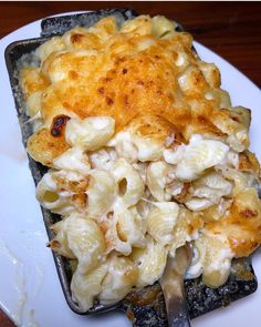 a white plate topped with macaroni and cheese on top of a wooden table