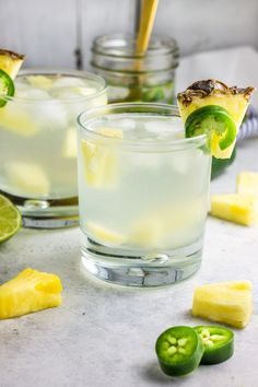 two glasses filled with lemonade and lime slices next to sliced jalapenos