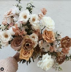 a person holding a bouquet of flowers in their hand with the background painted white and peach