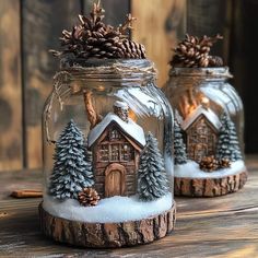 two glass jars filled with snow and pineconis on top of a wooden table