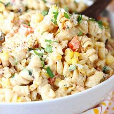 a white bowl filled with macaroni salad on top of a colorful table cloth