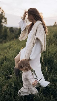 a woman and child standing in tall grass