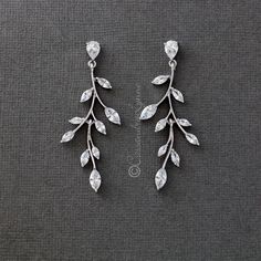 two pairs of earrings with leaves and stones on the bottom, one is white gold