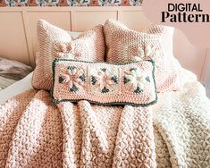 there is a crocheted blanket and pillow on the bed with two pillows that have flowers on them