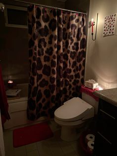 a bathroom with a leopard print shower curtain next to a white toilet and bathtub