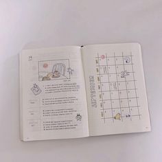 an open planner book on a white surface with writing and illustrations in the pages,