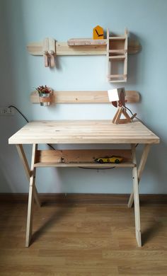 a wooden desk sitting on top of a hard wood floor next to a blue wall