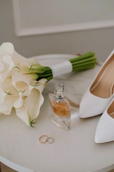 a bouquet of white flowers sitting on top of a table next to a pair of shoes