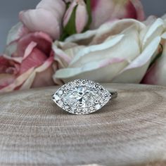 a diamond ring sitting on top of a piece of wood next to flowers and roses