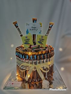 a birthday cake made out of beer bottles and wrapped in ribbon with lights on top