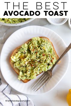 the best avocado toast recipe on a white plate with a fork and lemon wedges