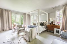 a bedroom with four poster bed, two chairs and a table in front of the window