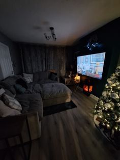 a bedroom with a christmas tree in the corner and a large screen on the wall