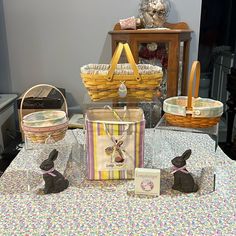 a table topped with baskets filled with easter eggs and bunnies on top of it