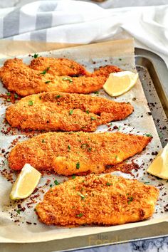 fish fillets with lemon wedges and parmesan cheese on a baking sheet