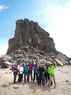 a group of people standing in front of a mountain