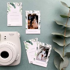 a white camera sitting on top of a table next to some cards and a plant