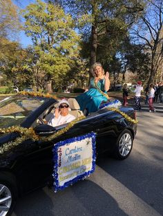 two people riding in a car with a sign on the back that says congratulations march