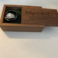 a wooden box with a wedding ring in it and moss growing out of the inside