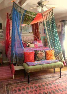 a canopy bed with many colorful pillows on it