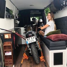 two people sitting in the back of a van with a motorcycle parked next to them