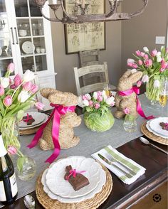 a dining room table set for easter with bunny decorations and flowers in vases on it